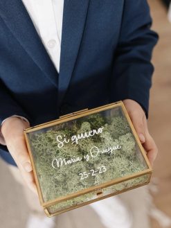 caja de cristal porta alianzas con relleno de musgo verde y letras blancas