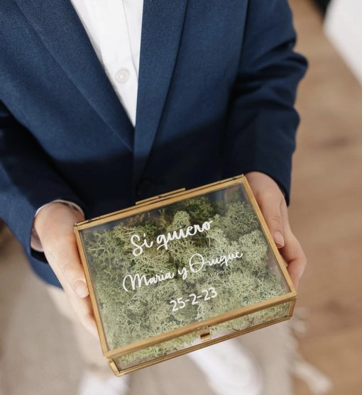 caja de cristal porta alianzas con relleno de musgo verde y letras blancas