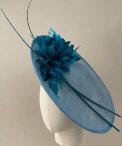 Tocado de sinamay con plumas al tono y raquis. Se coloca mediante una diadema. Disponible en dos colores. Perfecto para invitada y madrina.