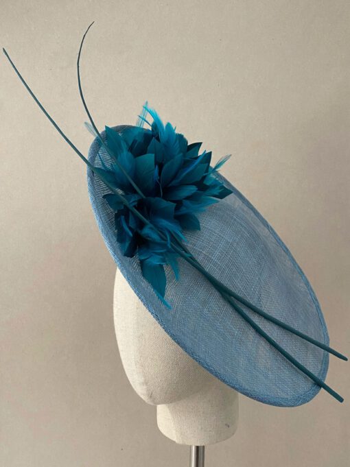 Tocado de sinamay con plumas al tono y raquis. Se coloca mediante una diadema. Disponible en dos colores. Perfecto para invitada y madrina.